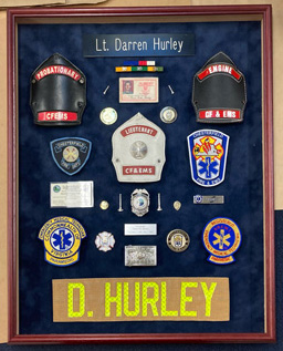 fireman's shields, badges and ribbons mounted in a framed shadowbox